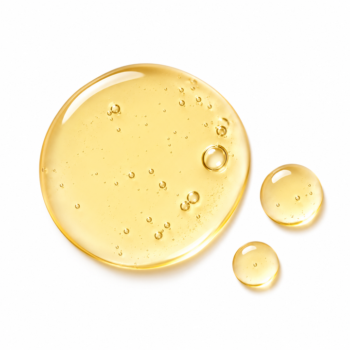 Three translucent golden-yellow liquid droplets on a clean white background, with a larger oval droplet in the center and two smaller round droplets to the right.