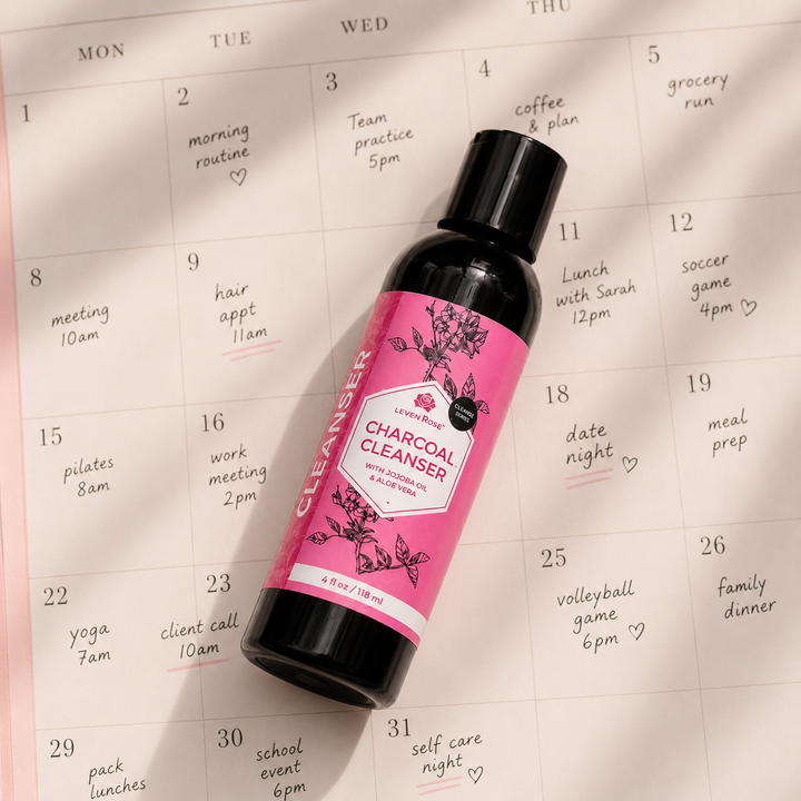 A bottle of Jane's Charcoal Cleanser resting diagonally on a printed monthly planner calendar page.