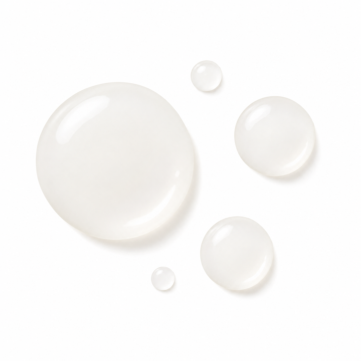 Four translucent, milky white cosmetic droplets of varying sizes on a solid white background.