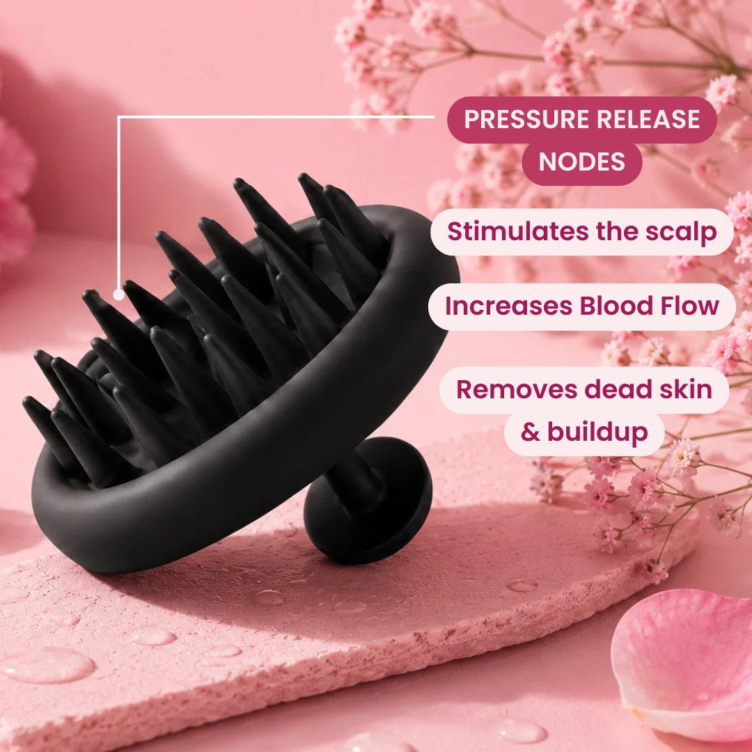 Black silicone scalp massage brush with pressure-release nodes, shown on a pink textured surface with decorative flowers and overlaid marketing text about scalp stimulation and blood flow.