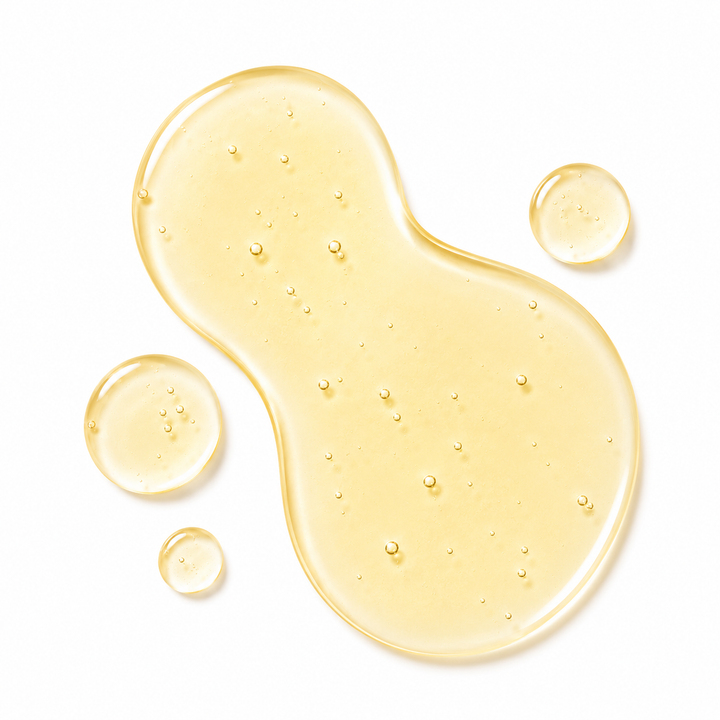 A translucent golden-yellow liquid cosmetic droplet with tiny air bubbles, shown on a clean white background.