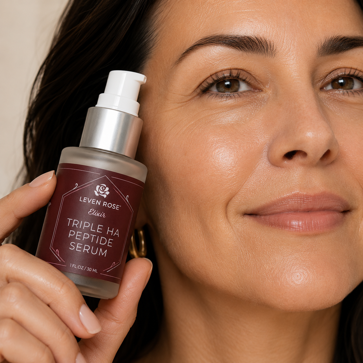 a woman holding the Triple HA peptide serum next to her face