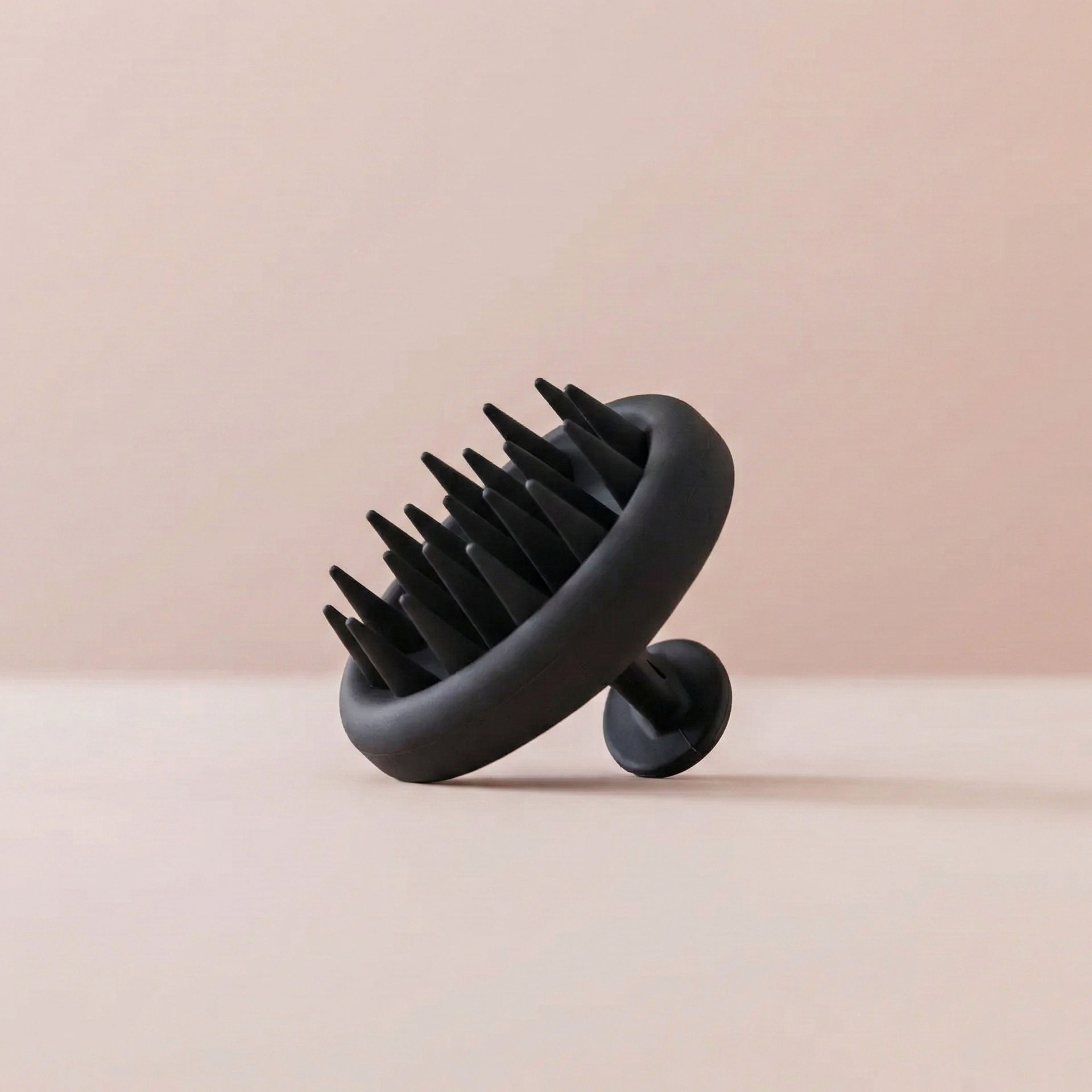 Black scalp massager on a beige background
