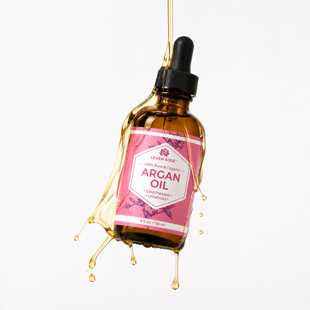 An amber glass dropper bottle of Leven Rose Argan Oil, suspended with a dramatic oil splash and droplet effect against a clean white background.