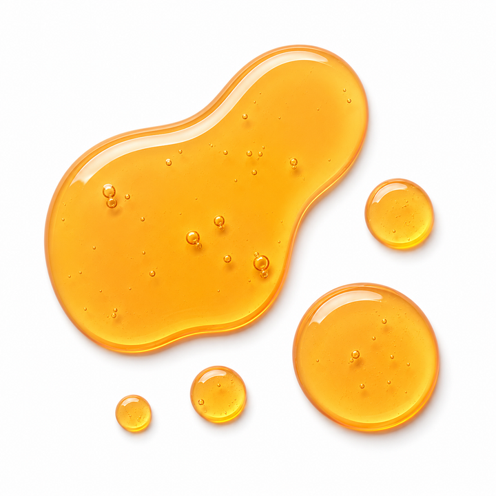 Golden translucent honey-like droplets and a larger irregular puddle on a clean white background.